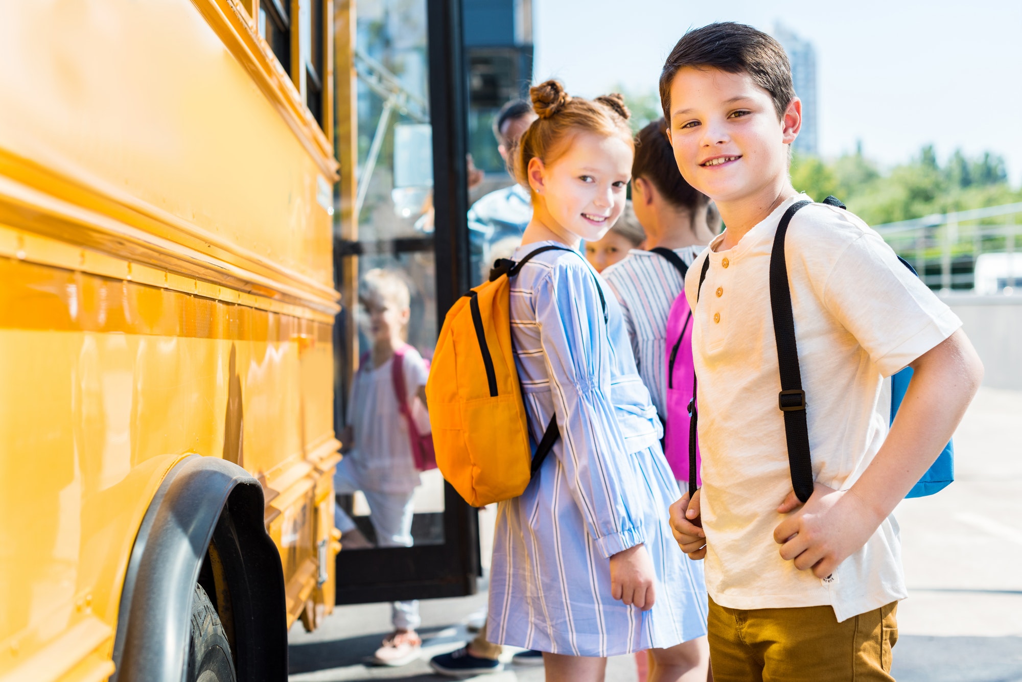 smiling little pupils entering school bus with classmates